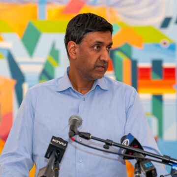 A man stands at a podium with microphones on it
