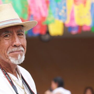 Un hombre con una camisa blanca y un sombrero mira a la cámara.