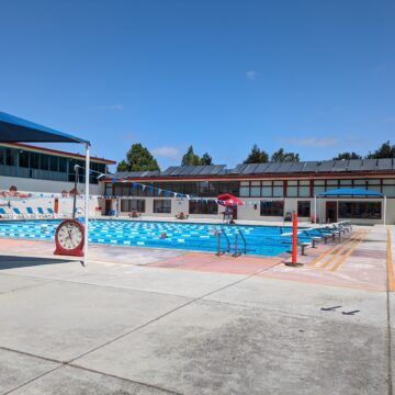 Una piscina dividida en carriles con nadadores haciendo largos.