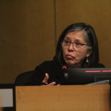 A woman sitting at a dais at a local government meeting