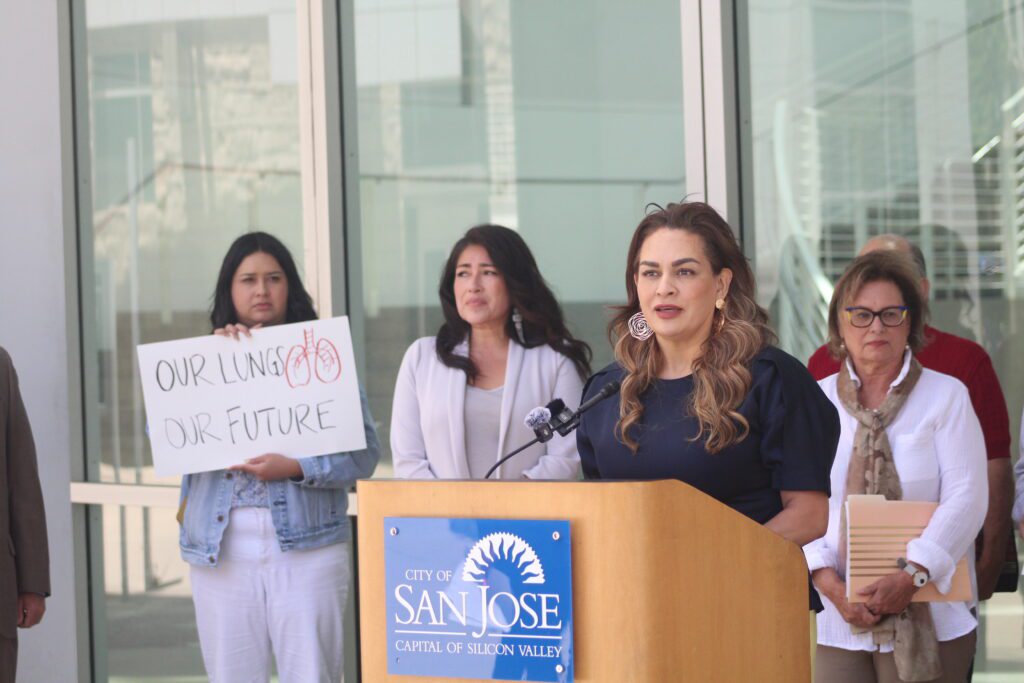 A woman standing in front of a podium with multiple other women in the background.