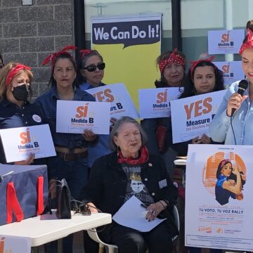 Mujer parada y sentada afuera con carteles políticos
