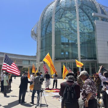 Người dân đi bộ trước Tòa thị chính ở San Jose, CA cầm cờ Mỹ và cờ Nam Việt Nam