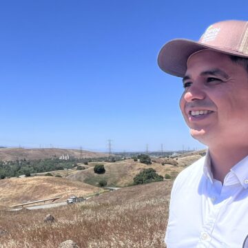 Un hombre con sombrero mira hacia un campo de hierba.