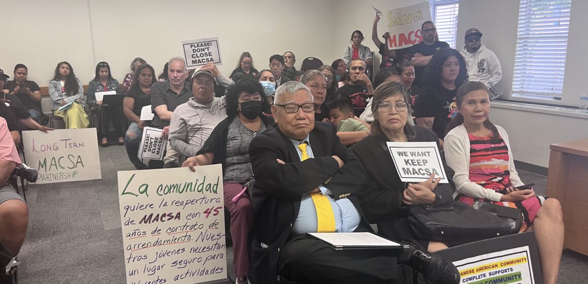 A group of people with protest signs at a school board meeting