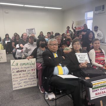 A group of people with protest signs at a school board meeting