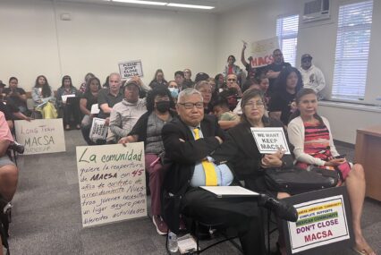 A group of people with protest signs at a school board meeting