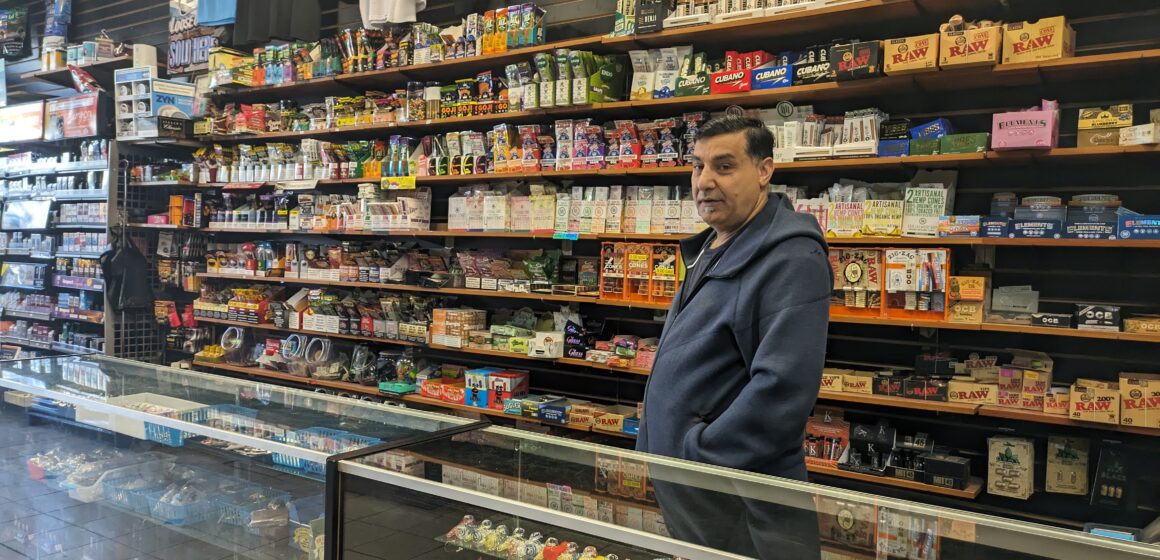 A man standing in a smokeshop, surrounded by shelves with drug paraphernalia