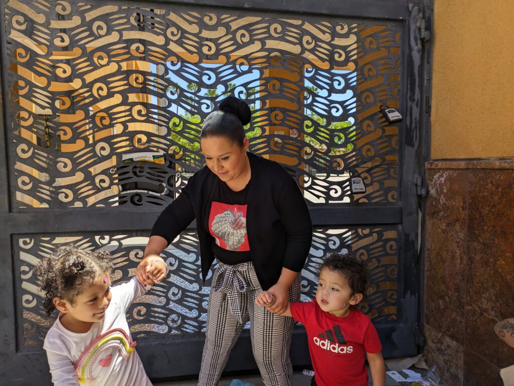 A woman wearing a bun wrangles her two young children, a boy and a girl