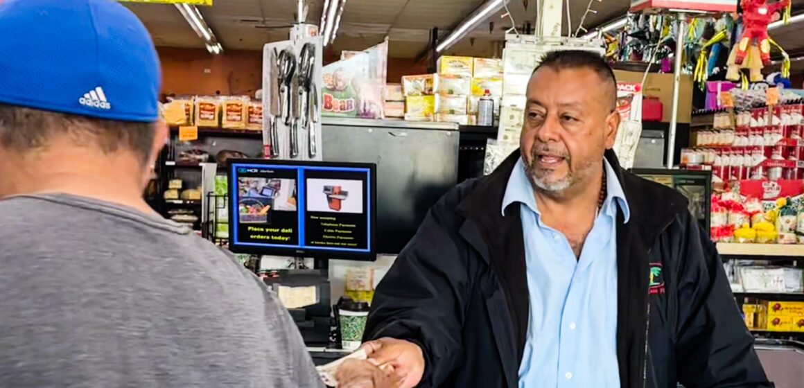 A business owner at the cash register is handing a customer cash back.