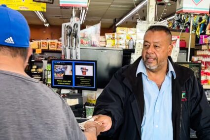 A business owner at the cash register is handing a customer cash back.