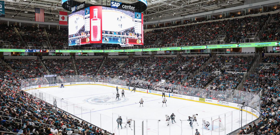Large hockey arena with fans watching players on the ice.