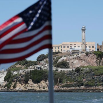 Alcatraz island outside of San Francisco, with an American flag in the foreground