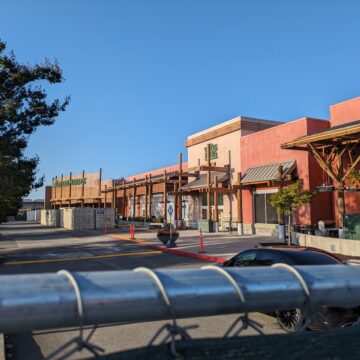 The outside of a large Whole Foods store with a metal fence in the bottom quarter of the photo.