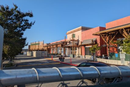 The outside of a large Whole Foods store with a metal fence in the bottom quarter of the photo.