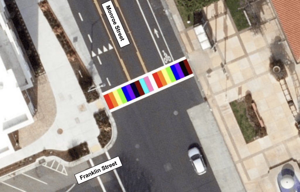 Streetview Screenshot of the Monroe Street intersection with a progress rainbow crosswalk photoshopped